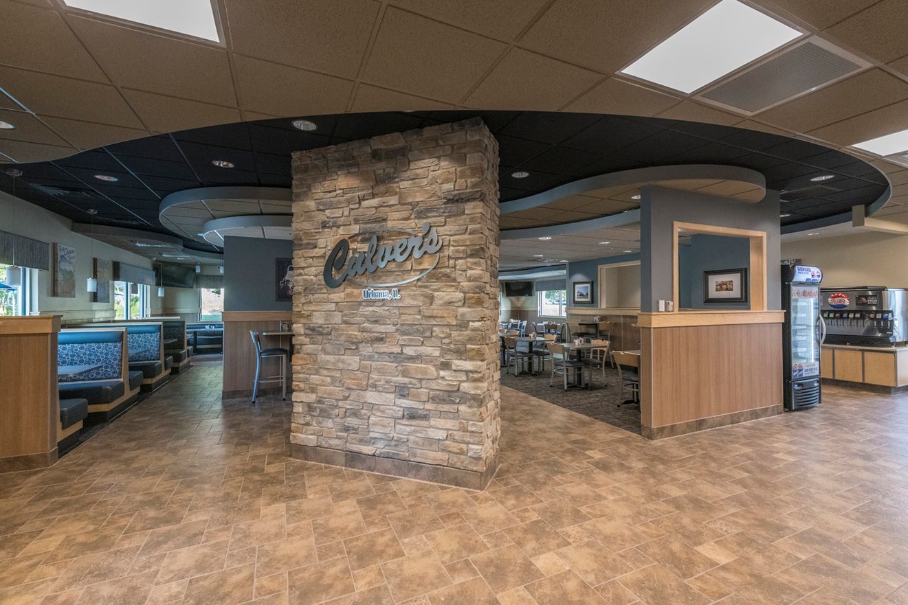 Interior of a restaurant with a stone pillar, booths, and a black ceiling.