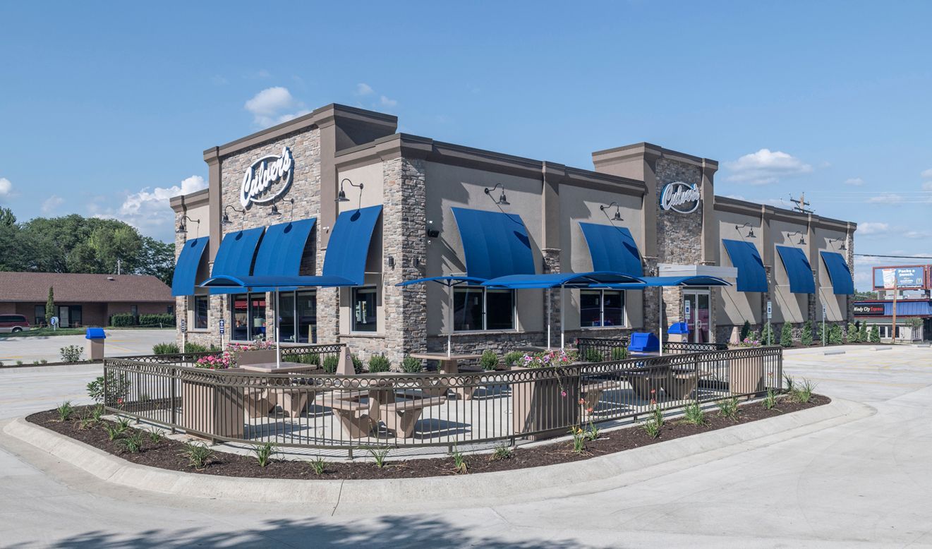 Exterior of a casual dining restaurant, featuring a beige building with blue awnings.