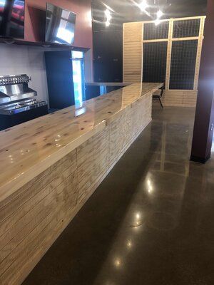 Long wooden bar in a restaurant, with a dark, polished floor.
