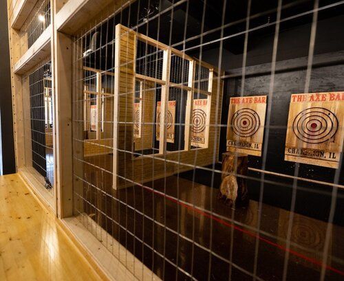 Axe-throwing lane: wooden targets, metal cage, and wood flooring inside 