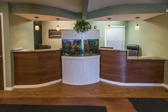 Reception area with two desks flanking an aquarium, neutral tones.