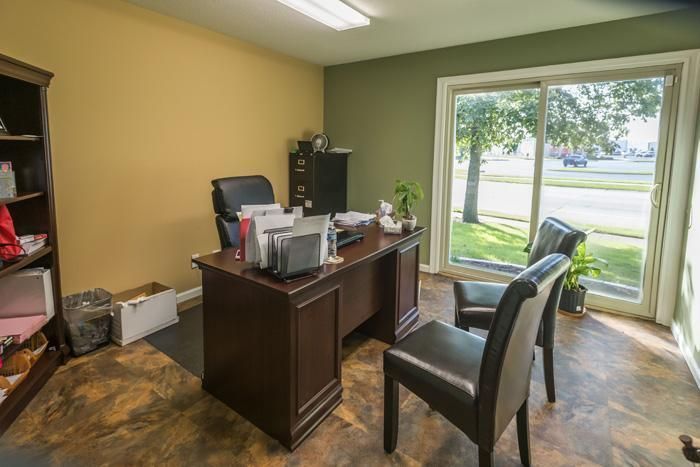 Office with a desk, two chairs, and a window overlooking a street. Walls are painted yellow and green.