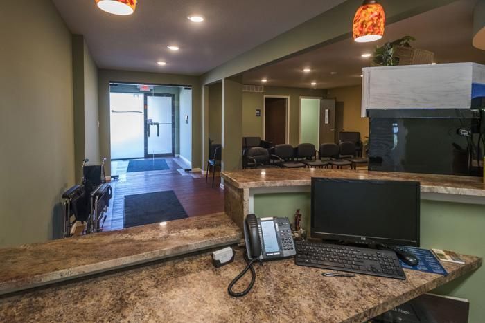 Reception area with a desk, computer, and waiting chairs.