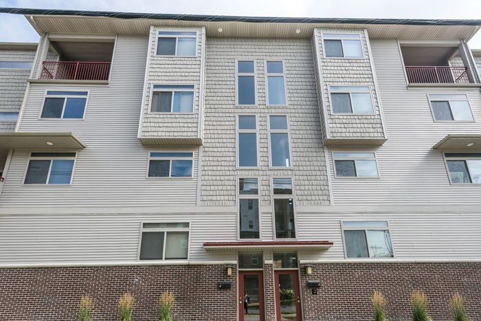 Multi-story building with beige siding, brick base, and tall windows.