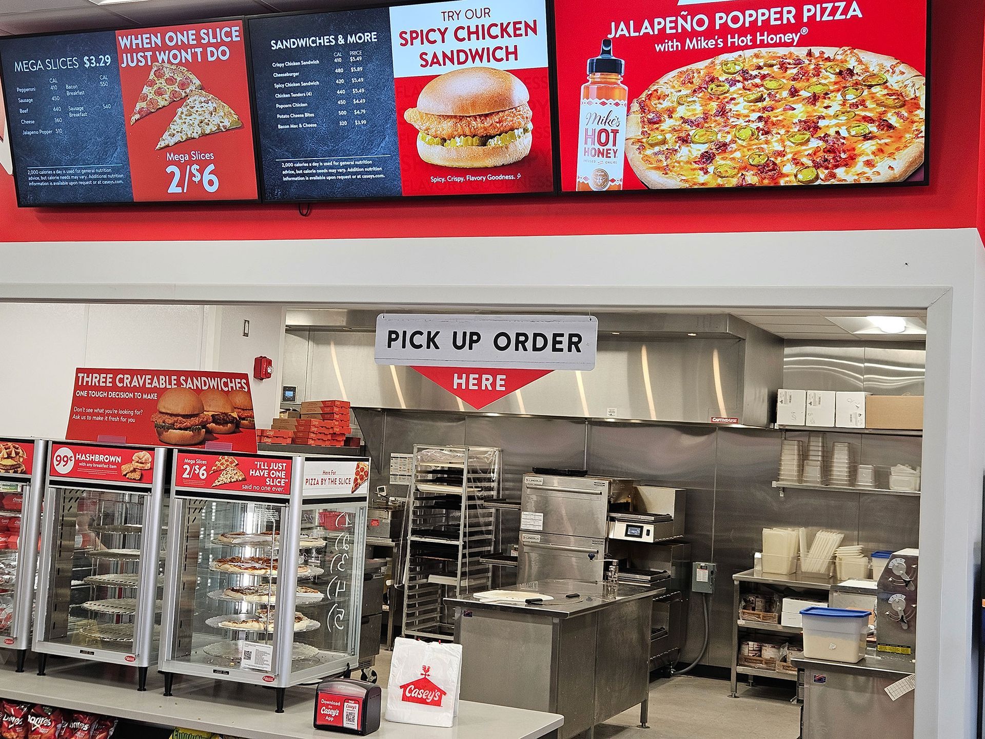 Interior of a convenience store, food prep area, menu boards, signage for pick up order.
