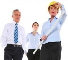 A man and two women are standing next to each other. the woman is wearing a hard hat