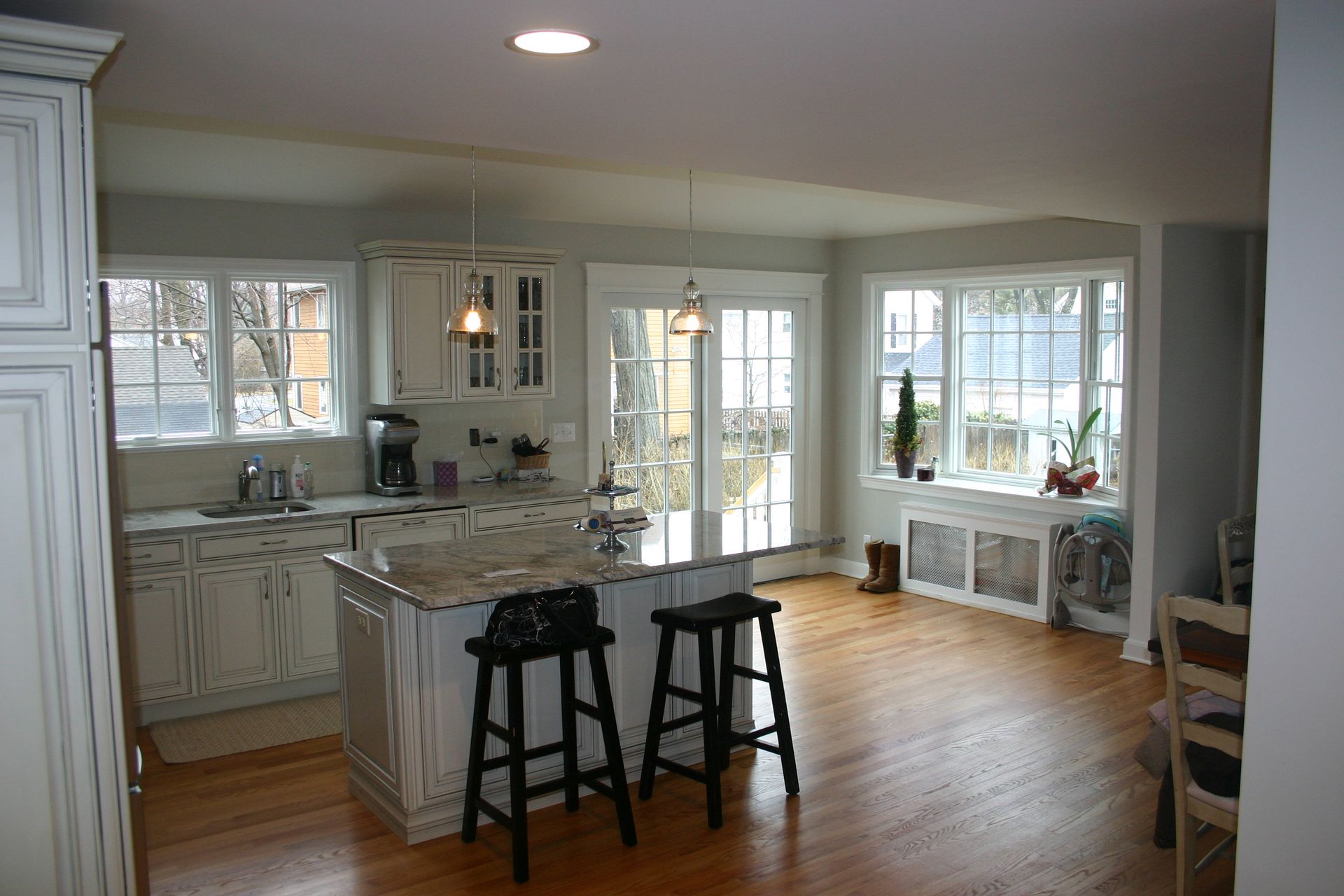 A kitchen with white cabinets and hardwood floors and stools
