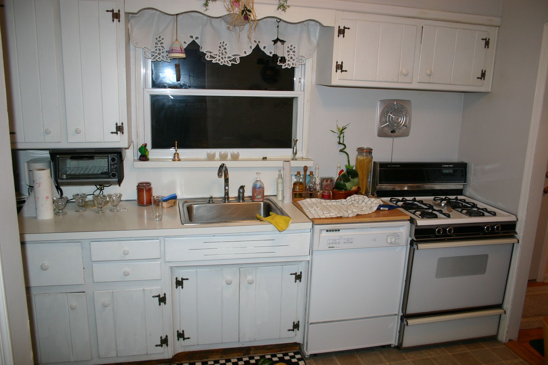 A kitchen with white cabinets and a stove and sink