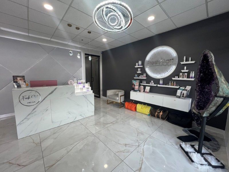 Modern spa reception area with white marble desk, product display, and large amethyst geode.