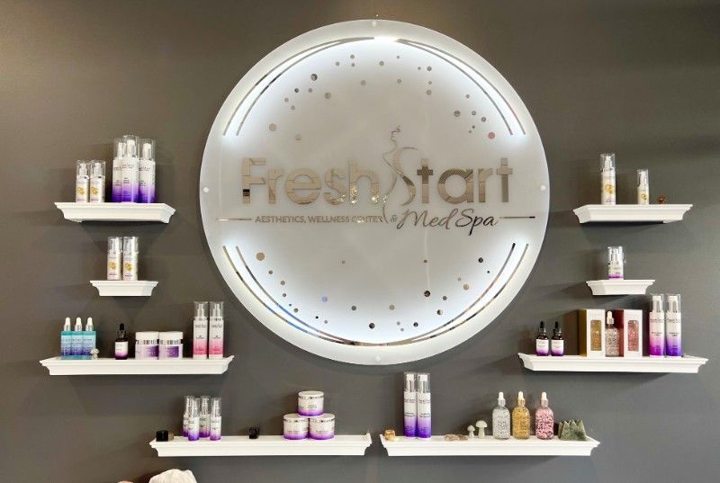 Fresh Start Med Spa sign on gray wall with illuminated circle and product shelves.