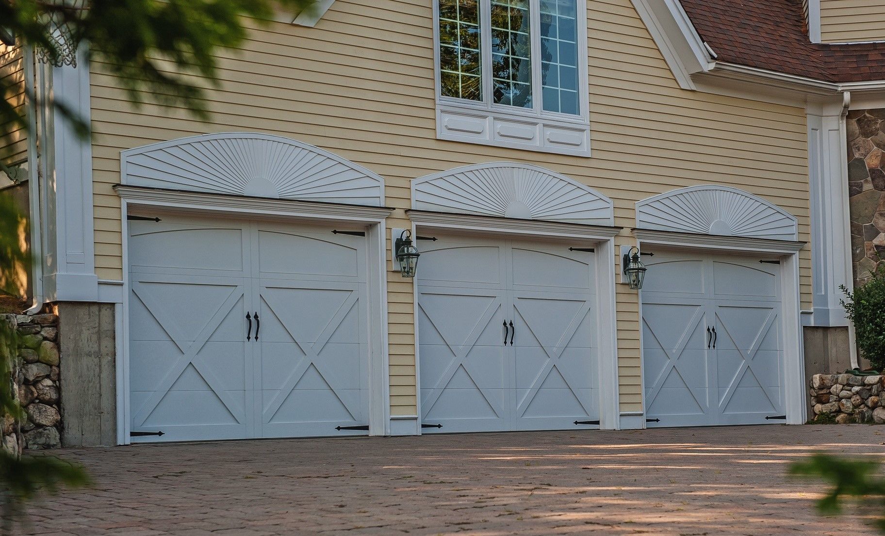There are three garage doors on the side of a house.