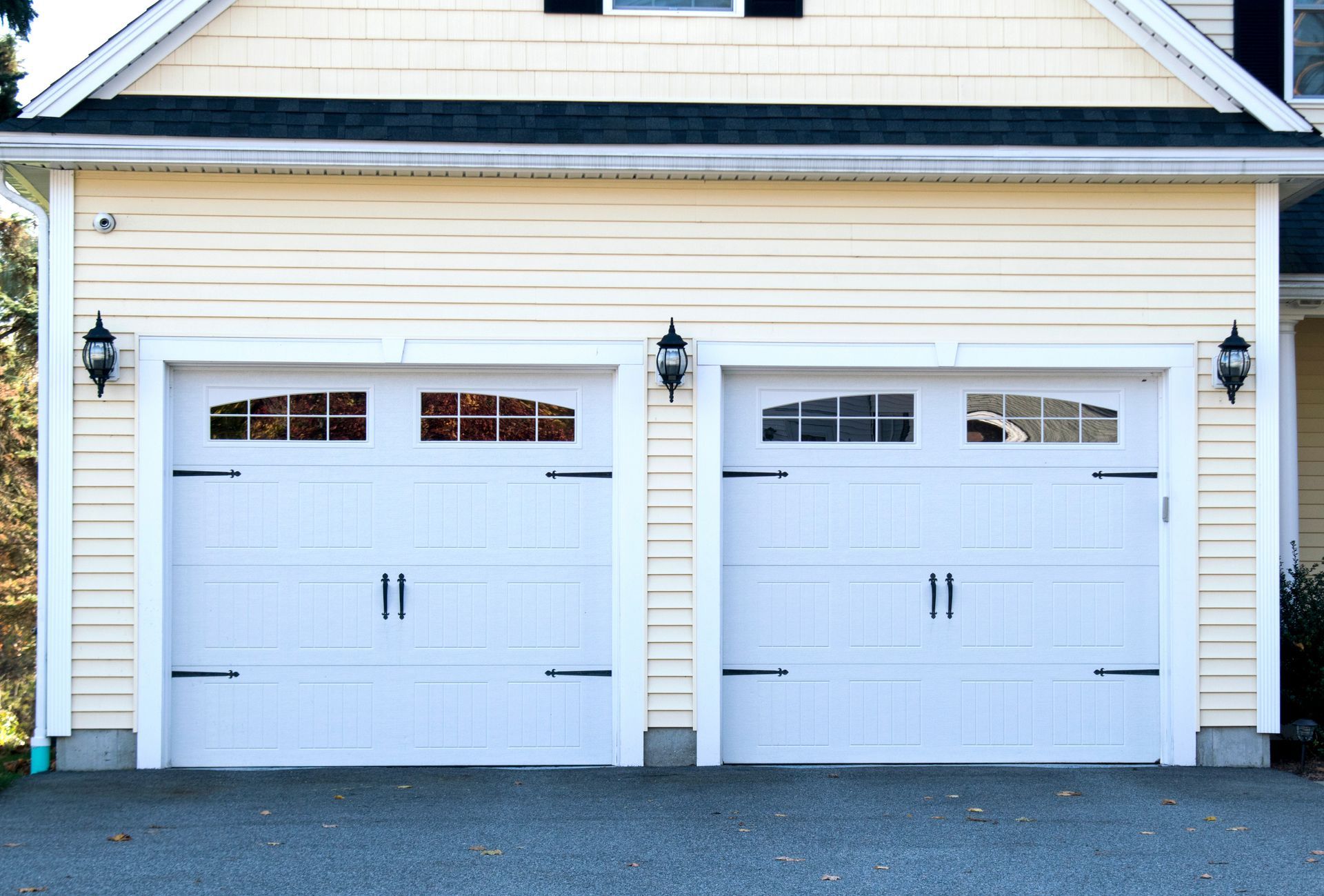 A house with two white garage doors and a black roof