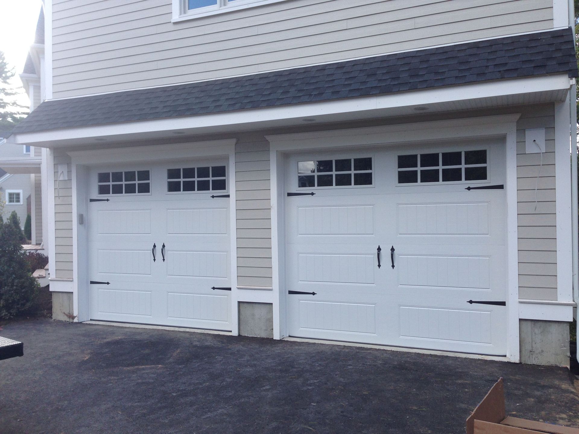 Two white garage doors on the side of a house