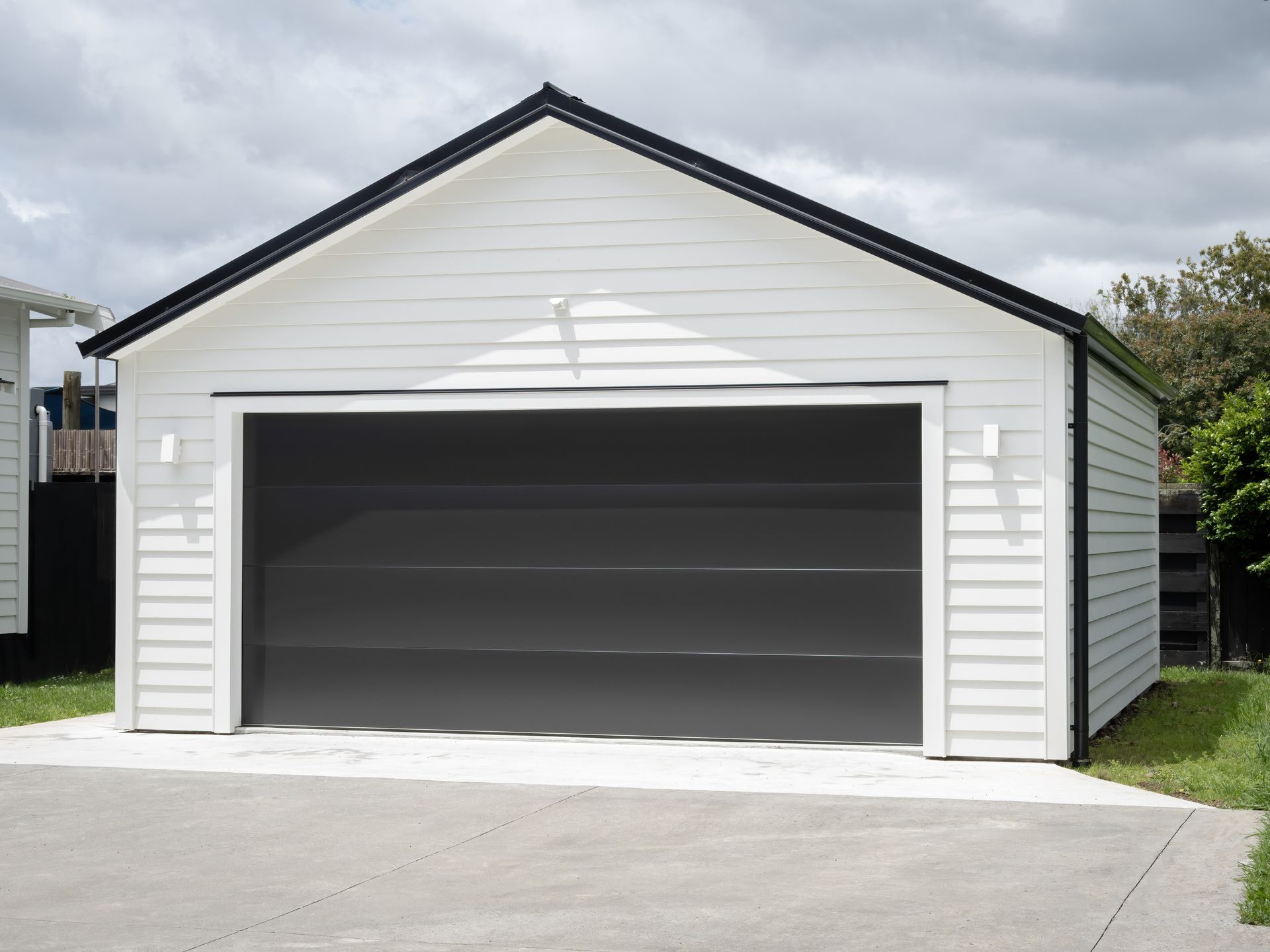 A white garage with a black door and a black roof