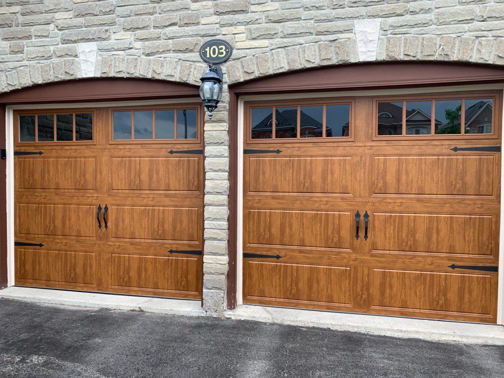 A pair of wooden garage doors on a brick building.