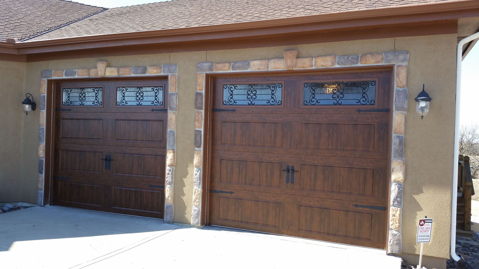 A garage with two wooden garage doors and a brick wall
