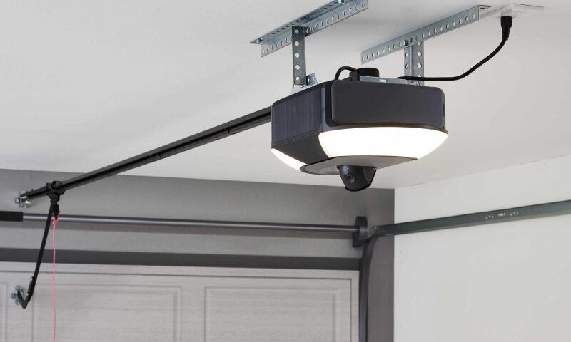 A garage door opener is hanging from the ceiling of a garage.
