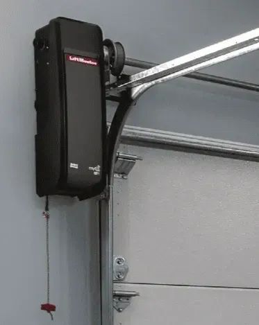 A garage door opener is mounted to the side of a garage door.