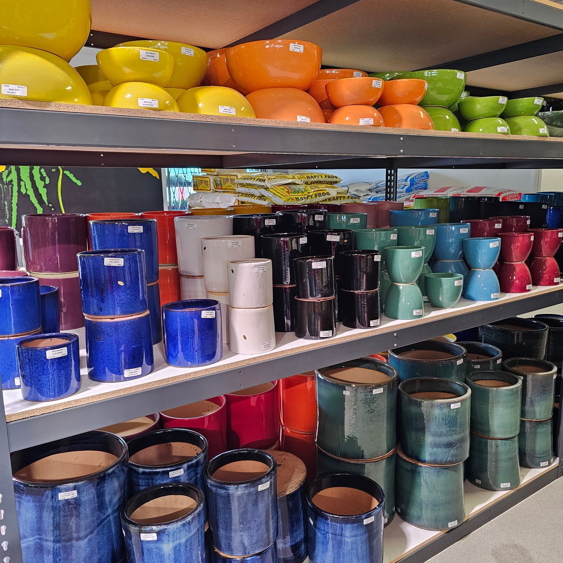 Shelves filled with colorful ceramic plant pots in various shapes and sizes.
