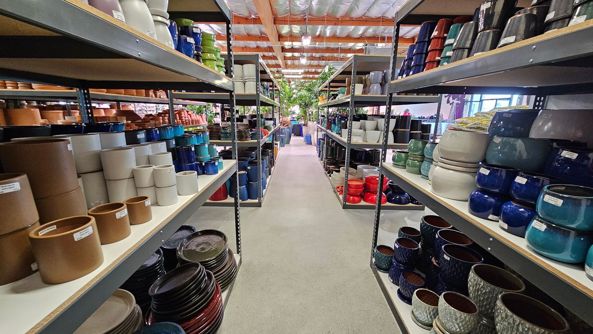 Shelves filled with various ceramic pots in a store, showcasing colors like brown, blue, and white.