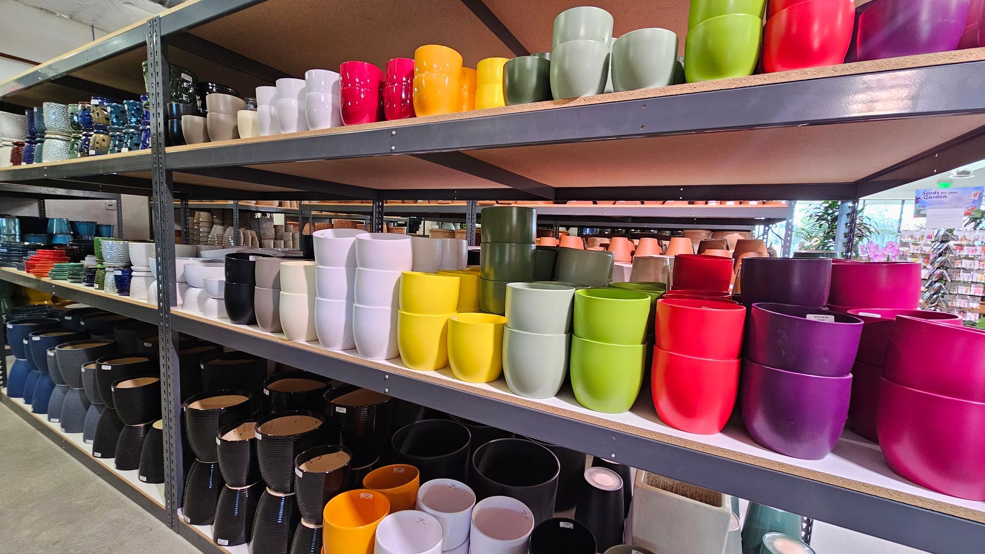 Shelves filled with colorful flower pots in various sizes, hues, and glossy finishes.