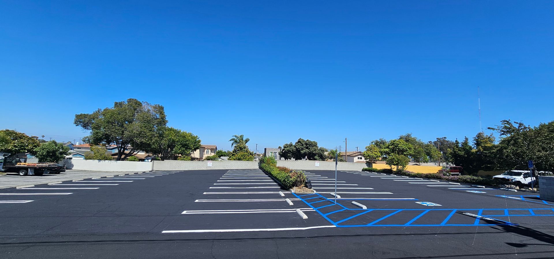 An empty parking lot with blue handicap spaces under a clear blue sky.