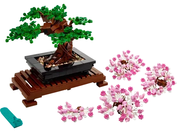 LEGO Bonsai tree model with green leaves and pink cherry blossoms on a dark wooden stand.