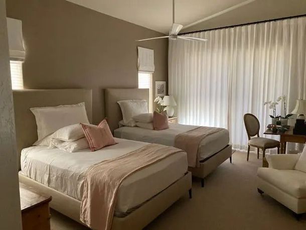 A bedroom with two beds and a ceiling fan