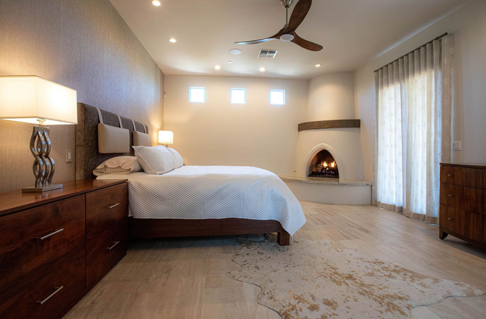 A bedroom with a king-size bed, a fireplace, and a ceiling fan.