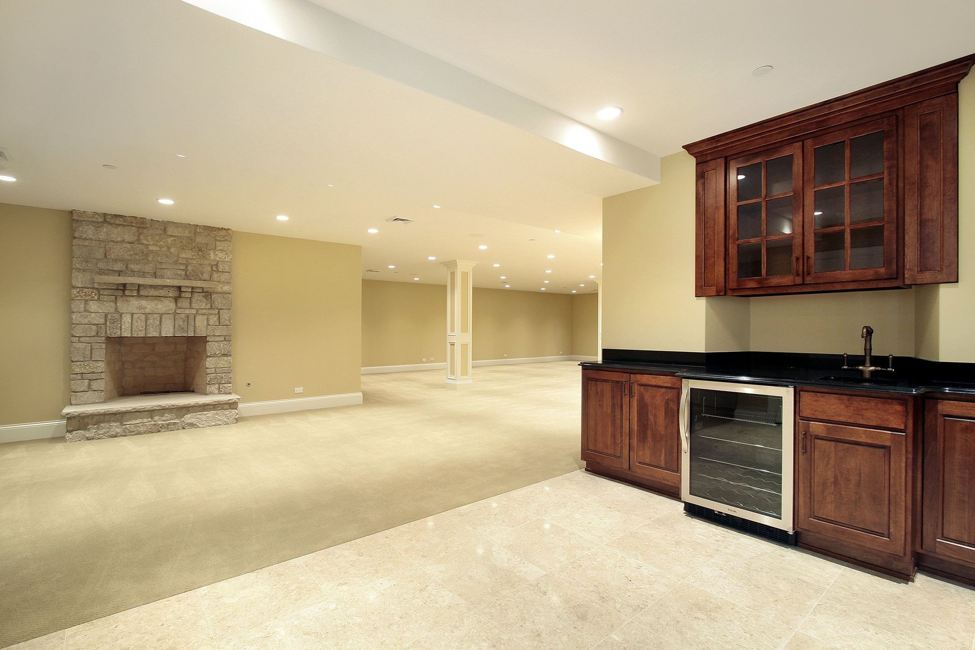 Spacious basement with a stone fireplace, bar area, and beige carpet.