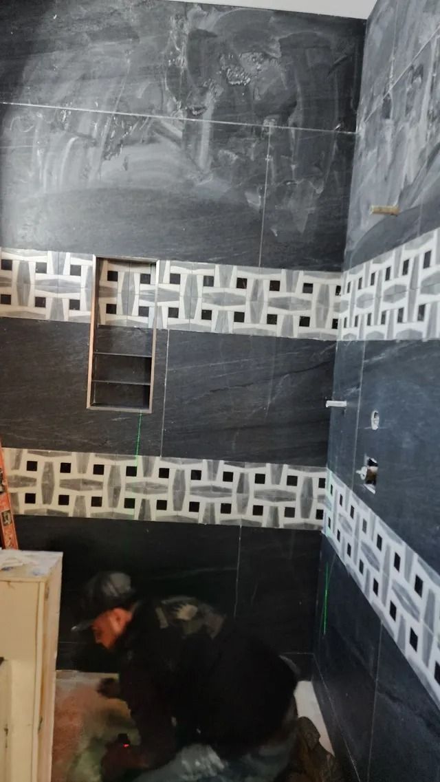 Bathroom under construction with black and white patterned tiles and a built-in shelf.
