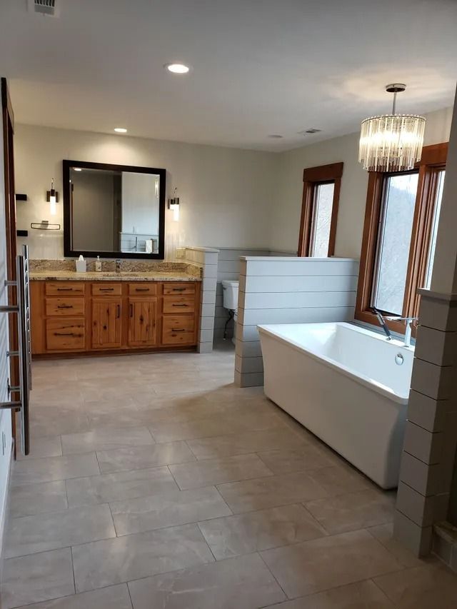 Spacious bathroom with a freestanding tub, double vanity with a large mirror, and light gray tiled floor.