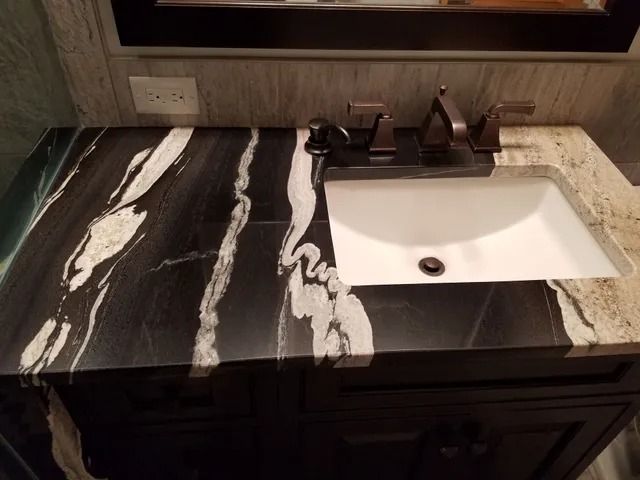 Black and white marble countertop with a white rectangular sink and black faucet.