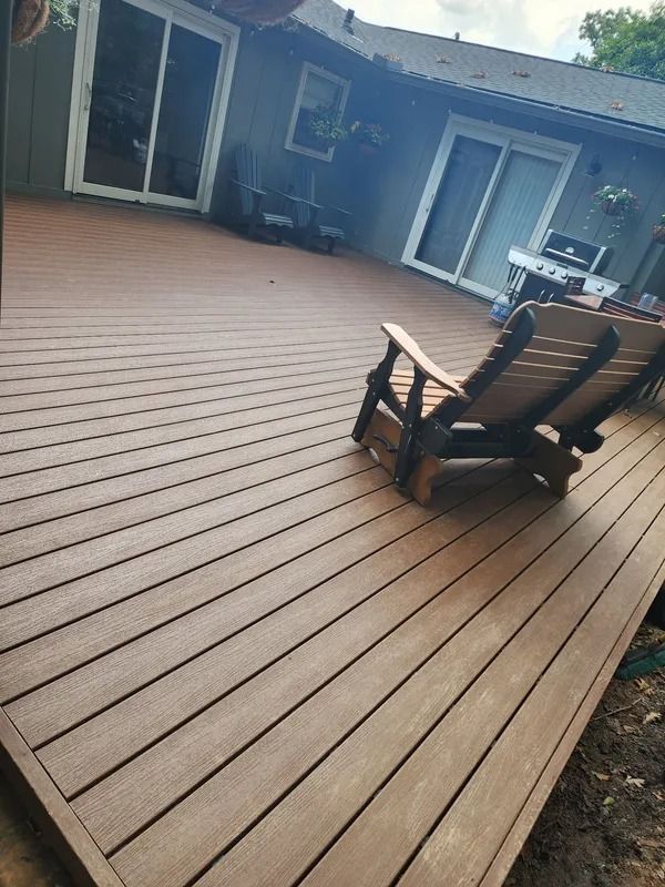 Wooden deck with two chairs, overlooking a house with sliding glass doors.