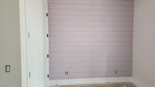 Room with light purple shiplap accent wall, white closet, and electrical outlets.