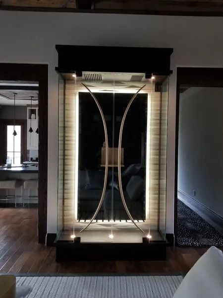 Decorative illuminated glass and metal feature built into a wall, flanked by doorways.