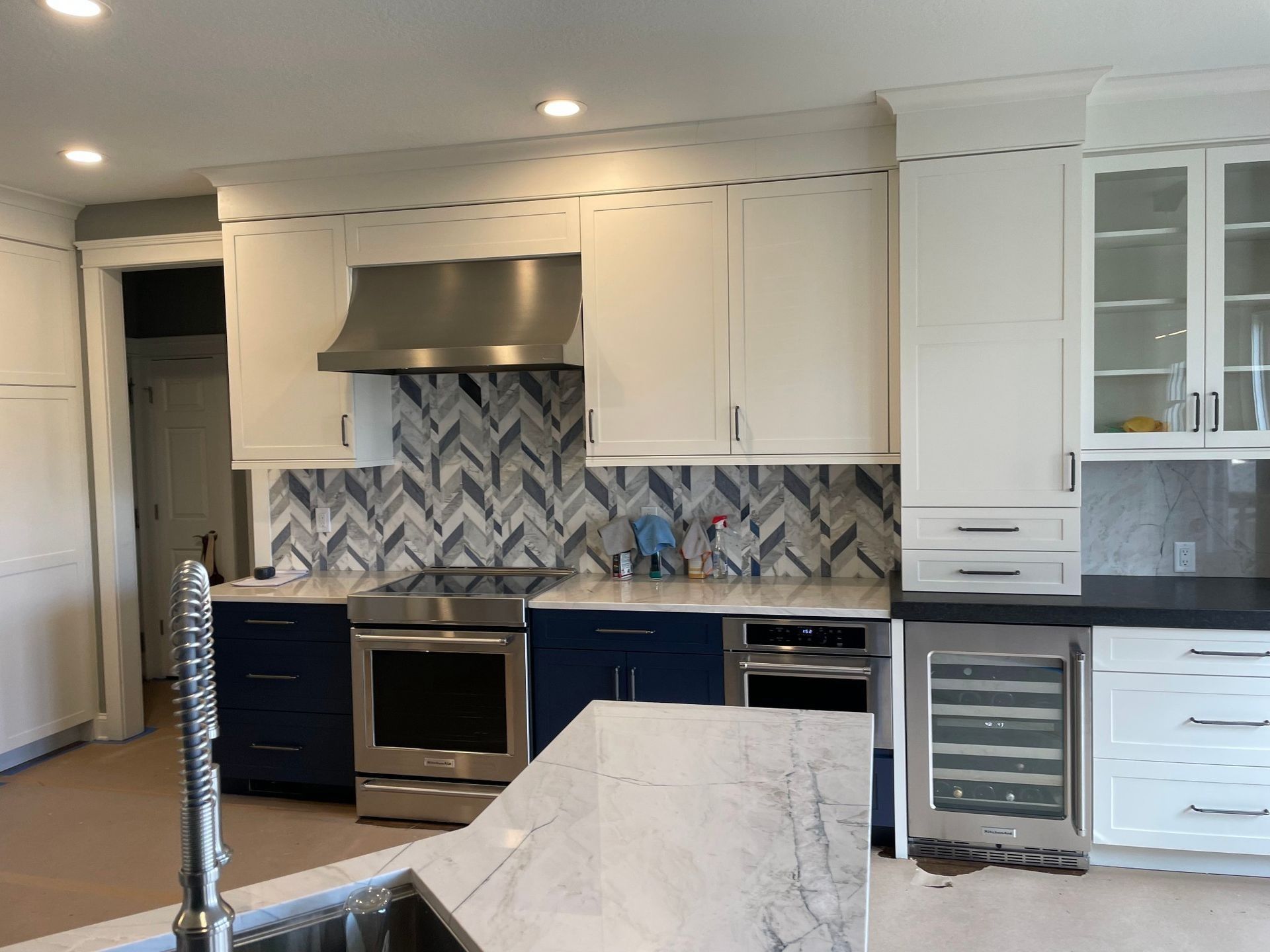 Kitchen with white and blue cabinets, stainless steel appliances, and a marble countertop.