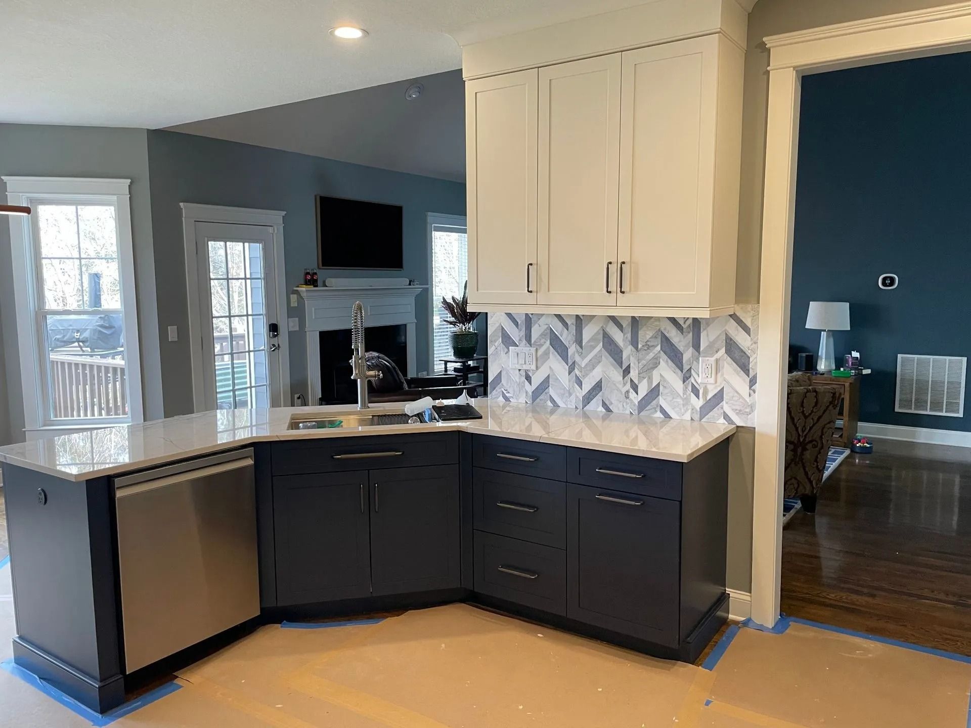 Modern kitchen remodel featuring blue and white cabinets, tile backsplash, and countertop island.
