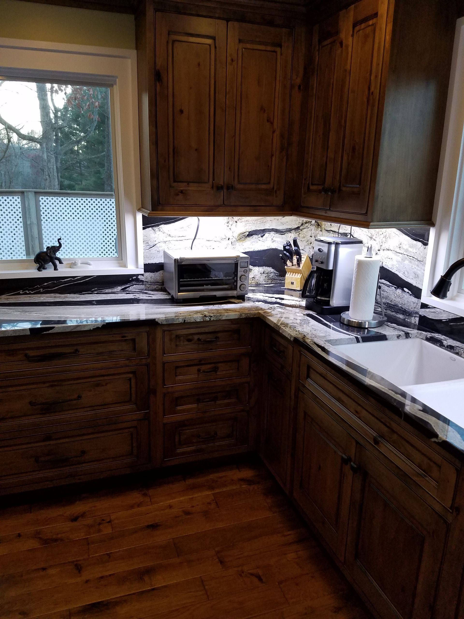 Kitchen with rustic wood cabinets and countertops, window, and appliances.
