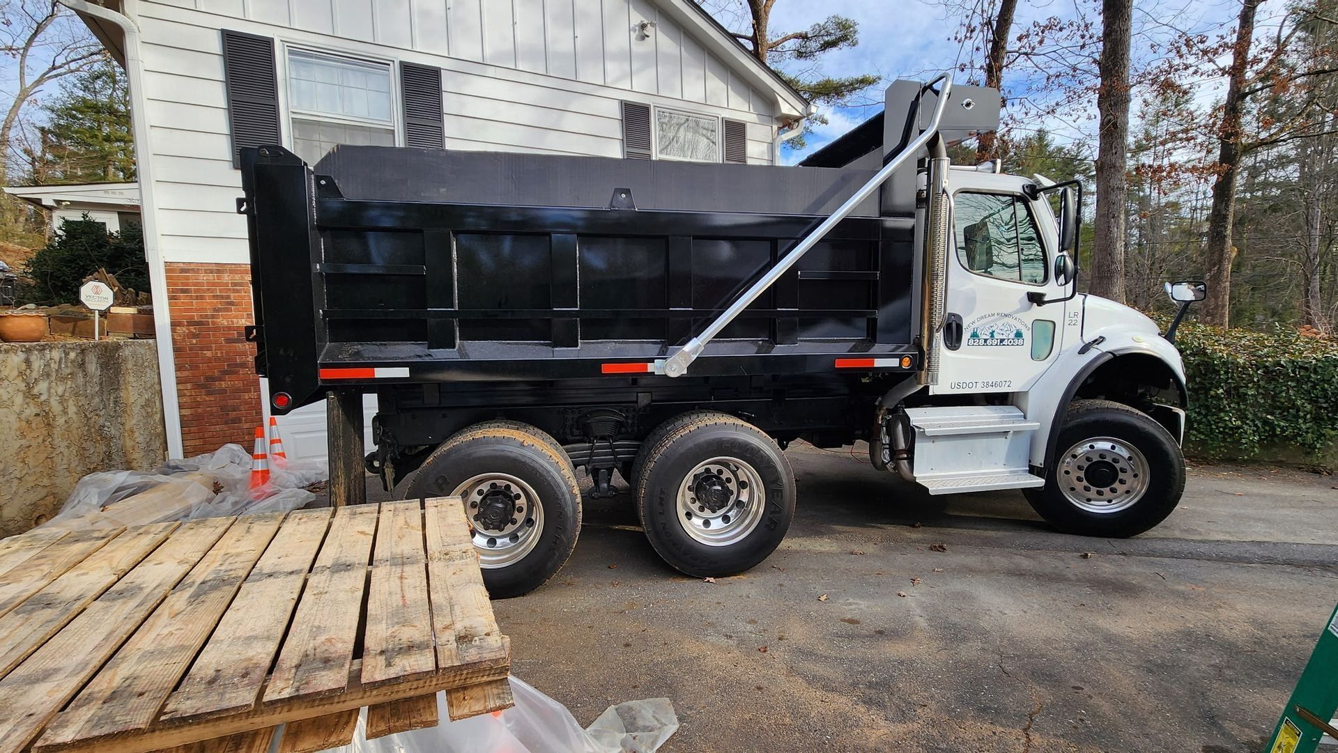Black dump truck parked near a house, preparing to unload.