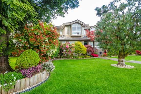 A large house with a lush green lawn and a lush green garden in front of it.
