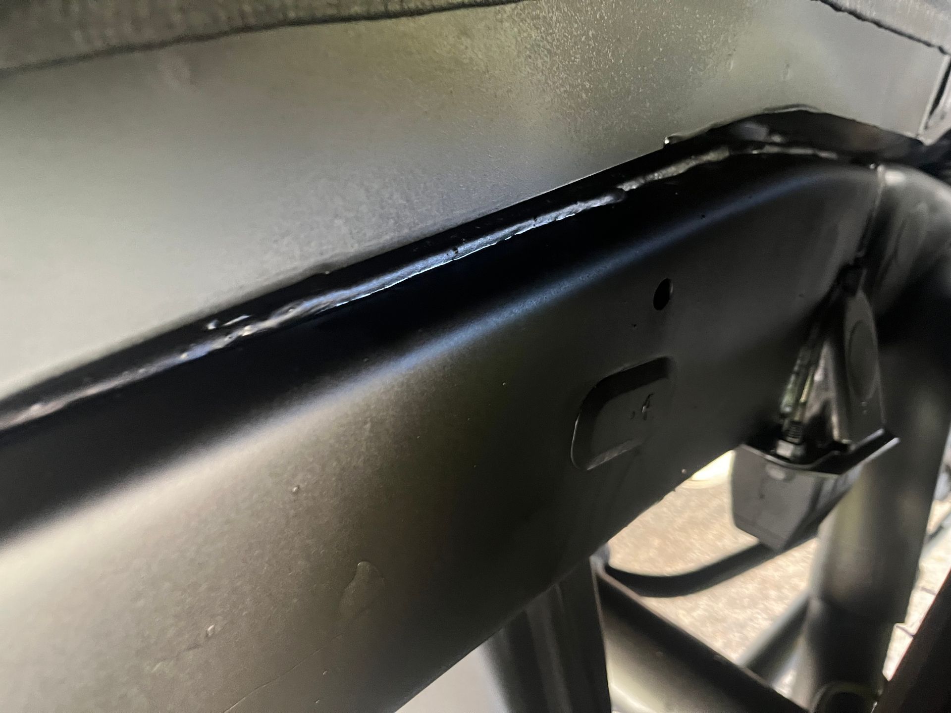 Underside view of a black truck chassis with a tire, exhaust, suspension components, and differential visible.