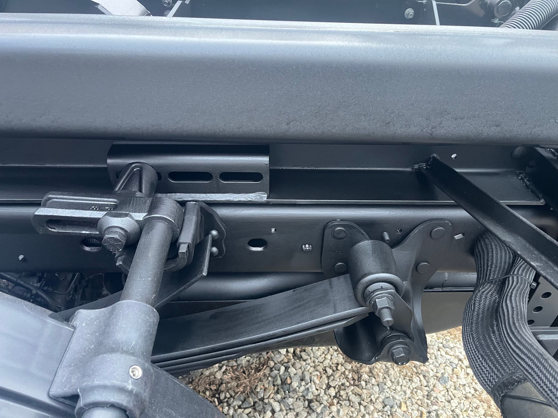 Black truck suspension detail: leaf spring, shock absorber, and mounting bracket.