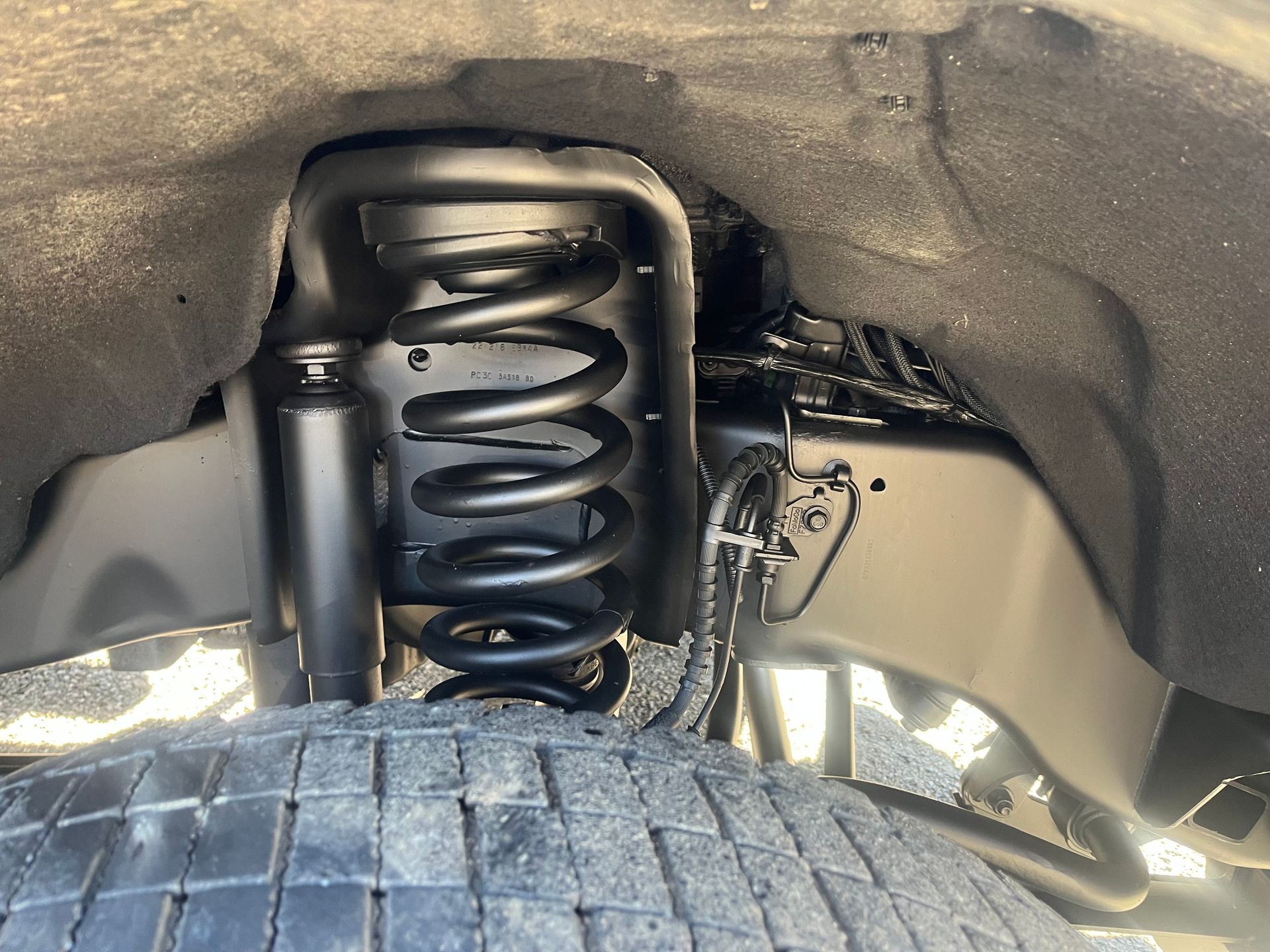 Black painted vehicle suspension with coil spring, shock absorber, and tire.