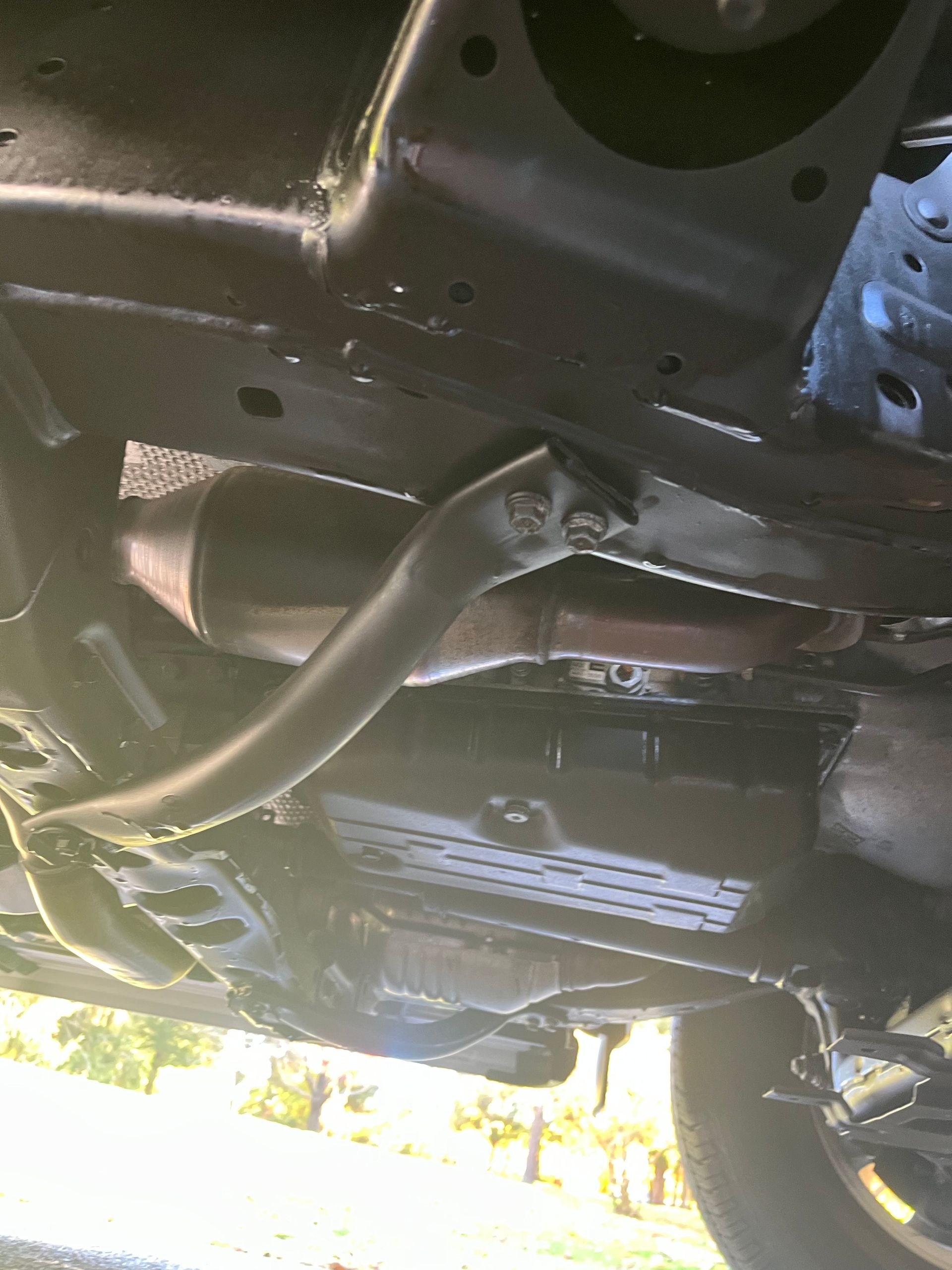 Black SUV covered in plastic wrap and green tape, possibly for painting or protection.