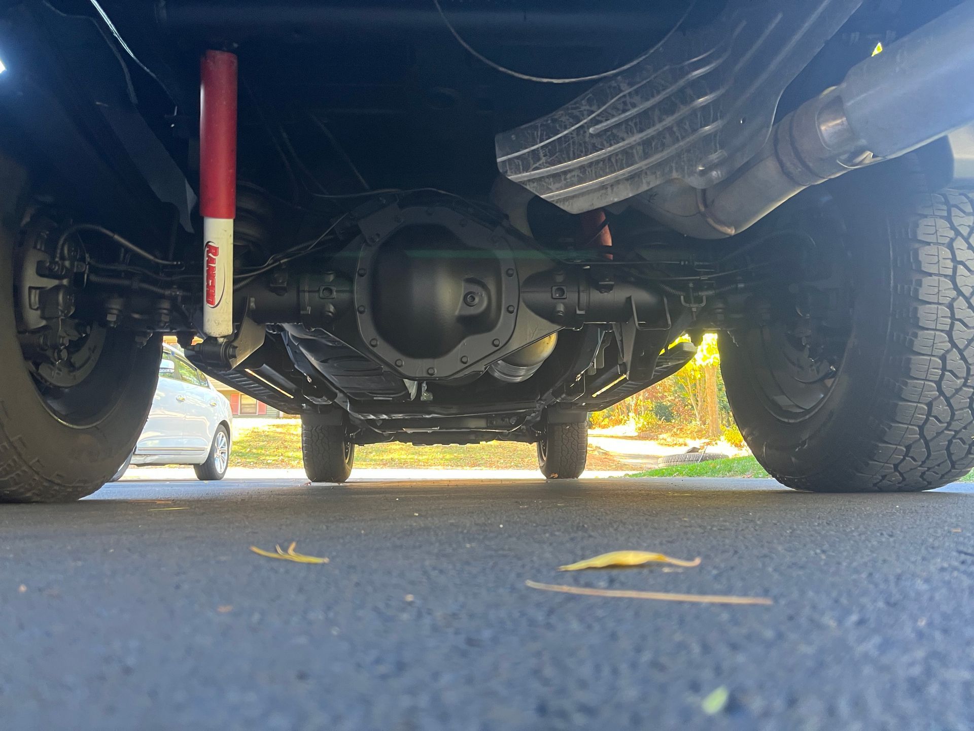 Underside of a black truck chassis with a central axle and red shock absorbers.