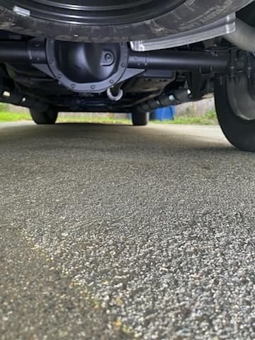 A close up of the underside of a car parked on a gravel road.