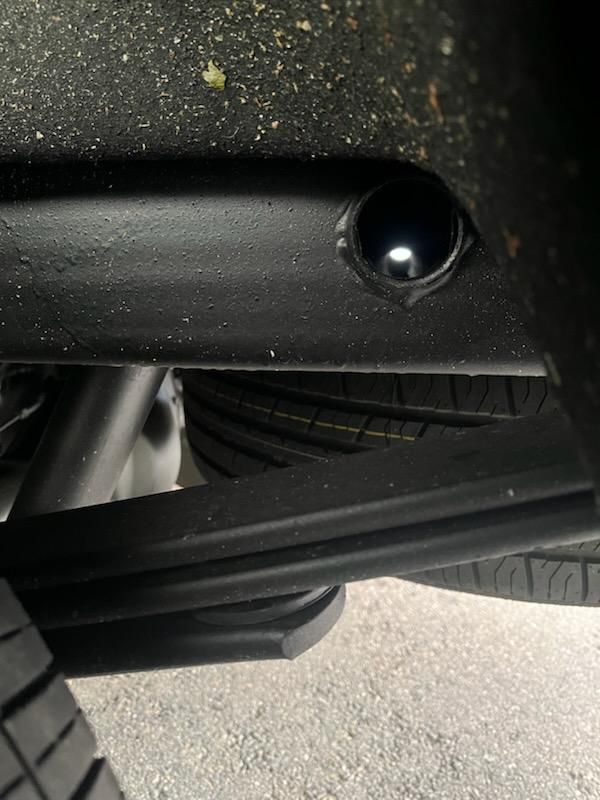 A close up of the underside of a car with a tire.