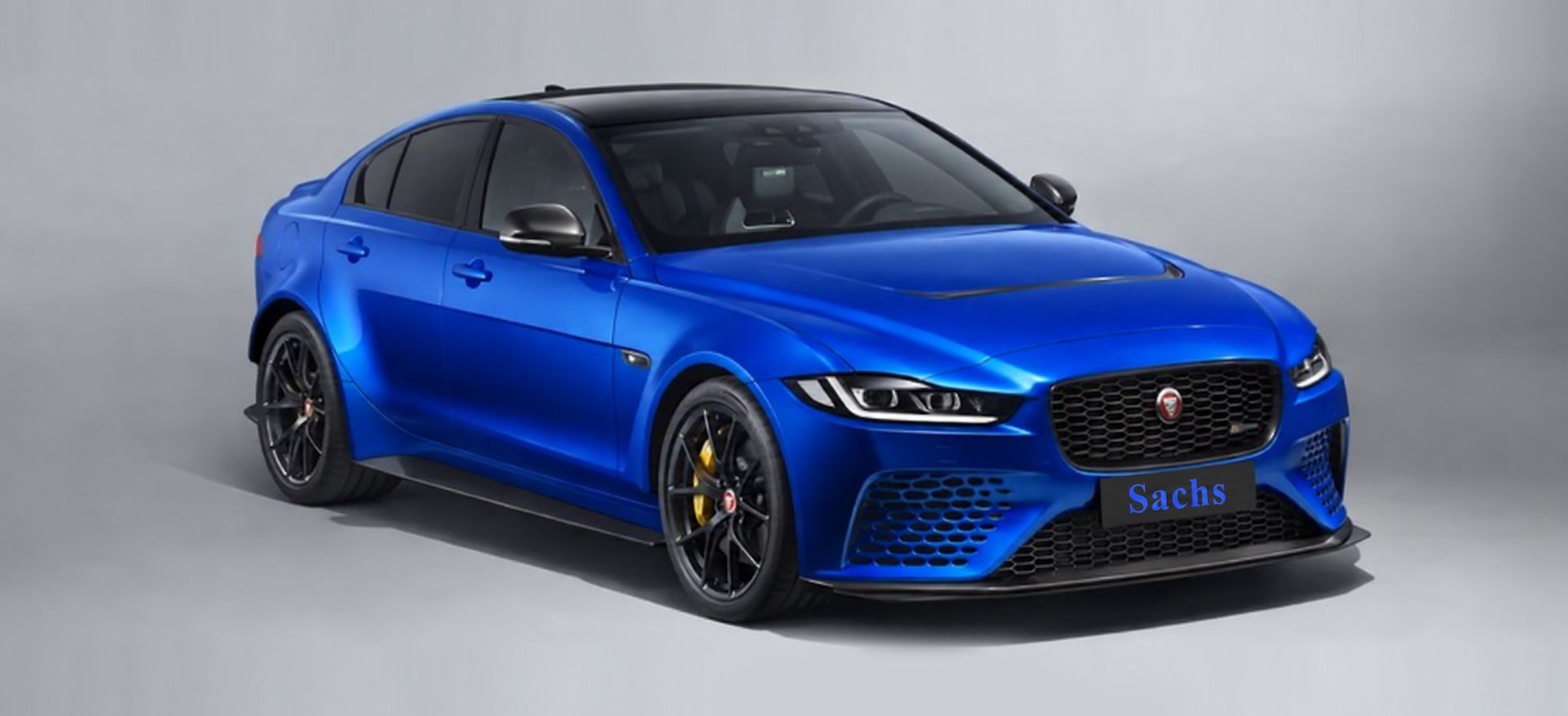Blue sports sedan in a studio, shown in front three-quarter view on a gray background.