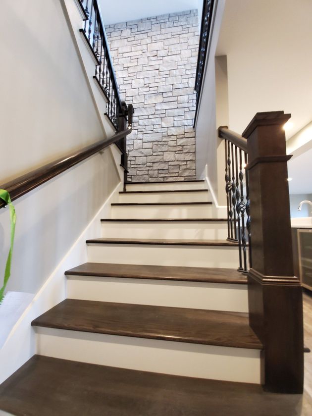 Indoor staircase with white risers, dark wood treads, and a brick accent wall at the landing